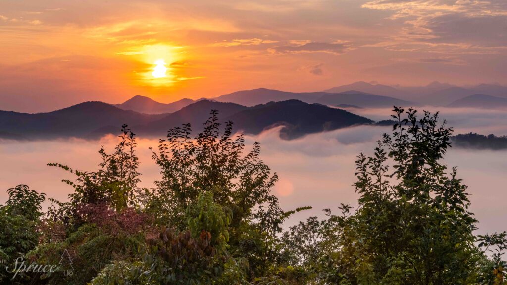 Sunrise in the Smoky Mountains with fog filling the valley and mountain peaks rising in the background.